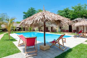 una piscina con 2 sillas y una sombrilla de paja en Blue Sky Resort en Nosy Be