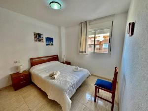 a bedroom with a bed and a chair and a window at Apartamento Costa Marina II REF. 020 in El Borseral