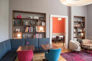 ein Wohnzimmer mit einem Sofa, Tischen und einem Bücherregal in der Unterkunft Small Luxury Hotel Altstadt Vienna in Wien
