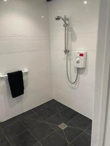 a bathroom with a shower with a black towel at Myrtle Cottage Boscastle in Boscastle