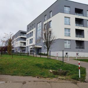 a building with a grassy area in front of a building at Włoski Apartament in Koszalin