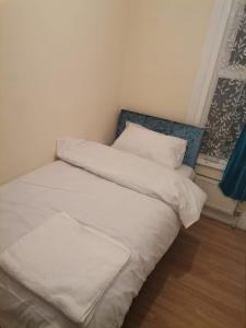 un letto con lenzuola e cuscini bianchi in una stanza di Nice Single Room near London Seven Kings Train station a Londra
