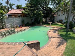 a pool of green water in a yard at Plum Cottage in Nelspruit