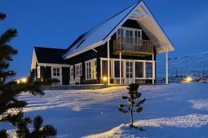 a house in the snow with a tree in the foreground at Efri-Rauðilækur in Hörgársveit in Akureyri