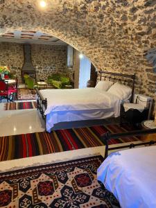 1 dormitorio con 2 camas y pared de piedra en Αρχοντικό Γκιντώνη en Levidhion