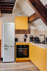 a kitchen with yellow cabinets and a white refrigerator at Gîte Tribü in Eaux-Bonnes