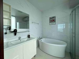 Baño blanco con bañera y lavamanos en Forest City King's Homestay 4R3T2604, en Gelang Patah