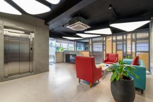 una hall con sedie rosse e una pianta in vaso di Eminent Suites and Apartments a Hyderabad