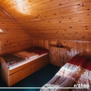 two beds in a cabin with wooden walls at N'SHPII VILLA in Peje