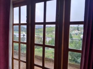 an open window with a view of a field outside at Creek View Inn in Nuwara Eliya