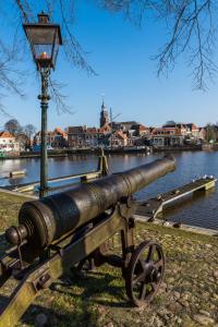 a cannon sitting on a bench next to a river at Watersportcamping Tussen de Diepen in Blokzijl