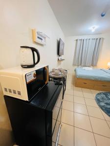 Zimmer mit einer Mikrowelle auf einem Tisch und einem Bett in der Unterkunft New 8 Spatial Davao Smart Studio Unit Netflix Wi-Fi Amazon Voice Controlled Lights in Davao City