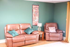 a living room with a leather couch and two chairs at Little Lodge on the Yorkshire Wolds in York
