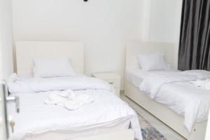 Diamond Guest House في الأقصر: سريرين في غرفة ذات أغطية بيضاء
