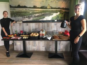 twee vrouwen die naast een tafel met eten staan bij Watersportcamping Tussen de Diepen in Blokzijl