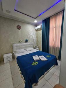 1 dormitorio con 1 cama azul y 2 toallas en Lux en Türkistan