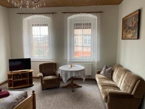 a living room with a couch and a table and two windows at Hotel Stadt Leipzig in Roßwein