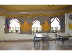 une chambre avec des tables et des chaises et des rideaux jaunes dans l'établissement Hotel Nutella Jaisalmer, Jaisalmer, à Jaisalmer