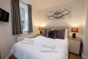 Un dormitorio con una gran cama blanca con dos lámparas. en Tan-Y-Ffordd - Tenby, en Tenby