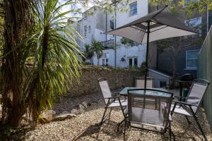 Una mesa y sillas con una sombrilla en un patio. en Tan-Y-Ffordd - Tenby, en Tenby