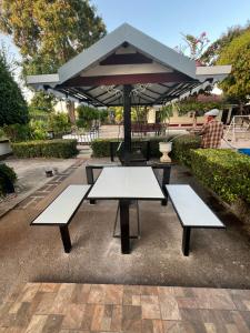 a picnic table with two benches and an umbrella at Suanpai Resort Sattahip in Ban Tao Than