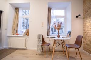 a dining room with a table and chairs and windows at Lukiskes square apartment (Oldtown) in Vilnius