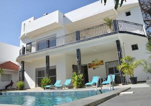 una villa con piscina di fronte a una casa di Magnifique villa climatisée avec piscine à Warang - Villa Keur Damel et Linguère a Ouoran