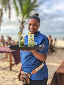 uma menina segurando uma bandeja com velas em uma praia em Aquarium Beach House em Nungwi