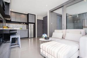 a living room with a white couch and a kitchen at Citygate Condo L704, near FantaSea & Café Del Mar Kamala Beach Club in Kamala Beach