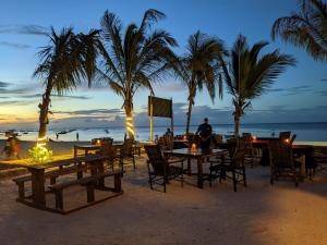 a man sitting at a table on the beach at Aquarium Beach House in Nungwi