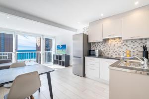 une cuisine avec des placards blancs et une table avec vue dans l'établissement Albatros 14-10 Estudio Levante Beach, à Benidorm