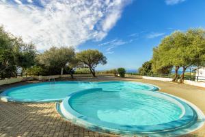 una gran piscina azul con árboles y el océano en Libeccio Sea view house, en Badesi