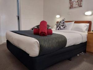 a large bed with two red stuffed animals on it at Golden Peak Motel PeakHill in Peak Hill