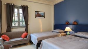 una camera con due letti e una sedia e una finestra di T Home Balcony Homestay a Hanoi