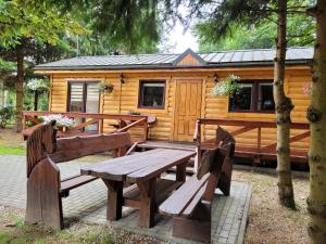 a wooden cabin with a wooden picnic table and benches at Domki drewniane pod Karpaczem in Mysłakowice