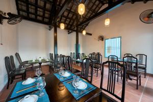 um restaurante com mesas e cadeiras num quarto em Legend Ancient Town Hoi An Hotel em Hoi An