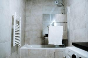 a bathroom with a tub and a shower with a towel at Appartement Paris La Défense U Arena in Nanterre