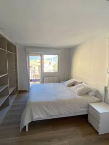 a white bedroom with a large bed and a window at Apartamento Elkano 1 in Hernani