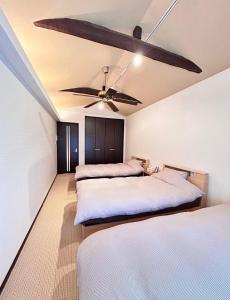 1 Schlafzimmer mit 3 Betten und einem Deckenventilator in der Unterkunft HimawariRyokanひまわり旅館 in Okayama
