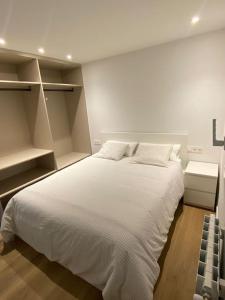 Un dormitorio con una gran cama blanca y estanterías en Apartamento Elkano 1, en Hernani