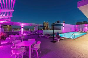 聖安東尼奧的住宿－Hilton Garden Inn San Antonio Downtown Riverwalk，一个带粉红色桌椅的屋顶露台和游泳池