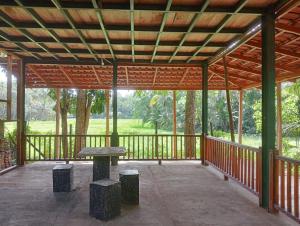 - un pavillon avec un banc et une table sur une terrasse couverte dans l'établissement Green Herbal Ayurvedic Eco-Chalets, à Galle