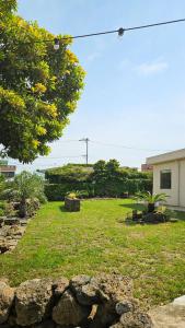a yard with grass and a building and trees at Aewol Gilro in Jeju