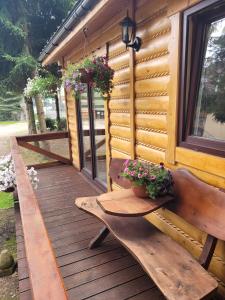 a wooden deck with a bench and flowers on it at Domki drewniane pod Karpaczem in Mysłakowice
