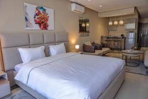 a bedroom with a large white bed and a living room at PLAYA DEL PACHA Suites Hotel in Marina Smir