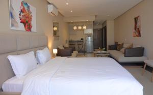 a bedroom with a large white bed and a living room at PLAYA DEL PACHA Suites Hotel in Marina Smir
