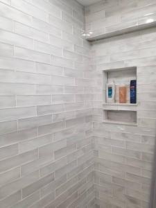 a bathroom with white tiled walls and a shelf at Cozy Center City Cottage*Walk to center city in Charlotte +19 photos