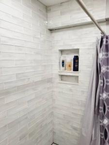 a bathroom with white tiled walls and a shower stall at Cozy Center City Cottage*Walk to center city in Charlotte