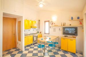 una cocina con armarios amarillos y una mesa con taburetes en Giglio Viola, en Campese