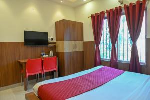Un dormitorio con una cama, un escritorio y un televisor. en Magnolia Inn near GNRC & Secretariat GS Rd, en Guwahati
